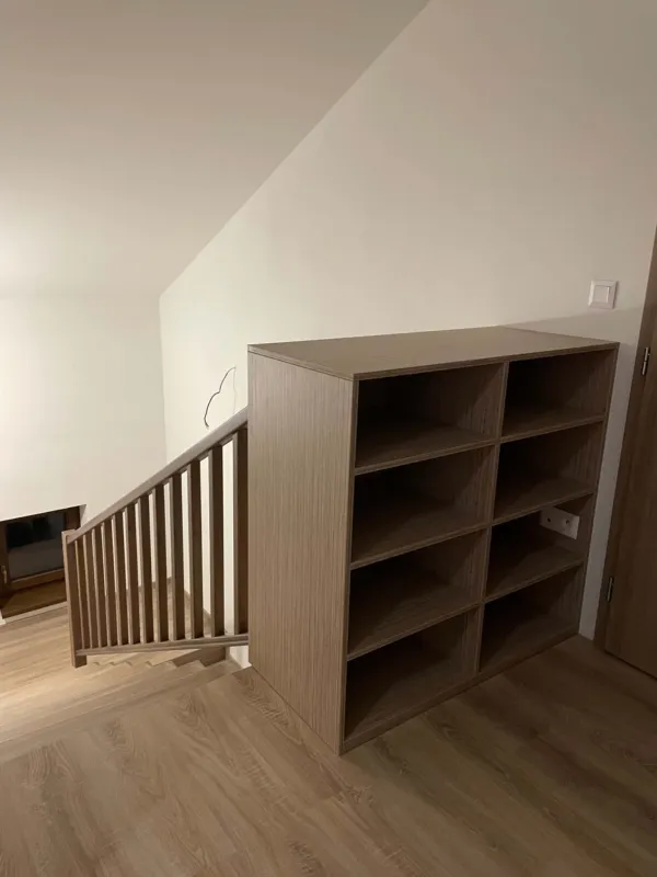 Drevené zábradlie schodiska a otvorený regál v podkroví