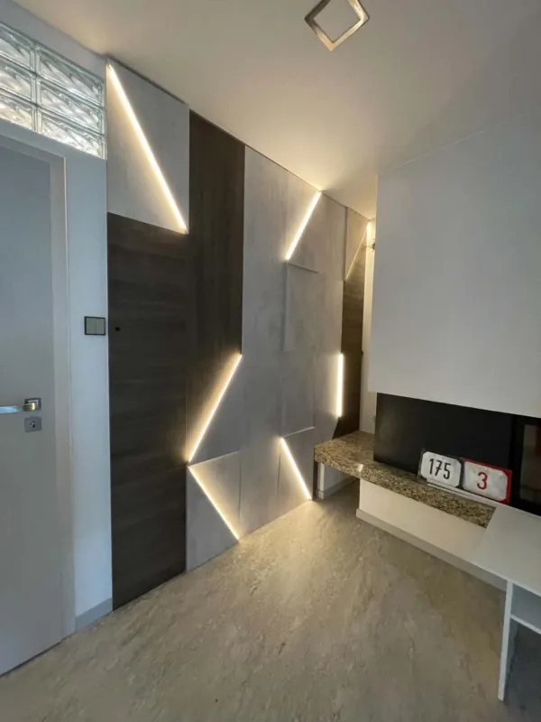 Obklad steny v obývačke s geometrickým LED podsvietením a dverami v dekore dreva