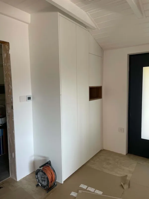 Biela vstavaná skriňa v podkrovnej predsieni s drevenou nikou