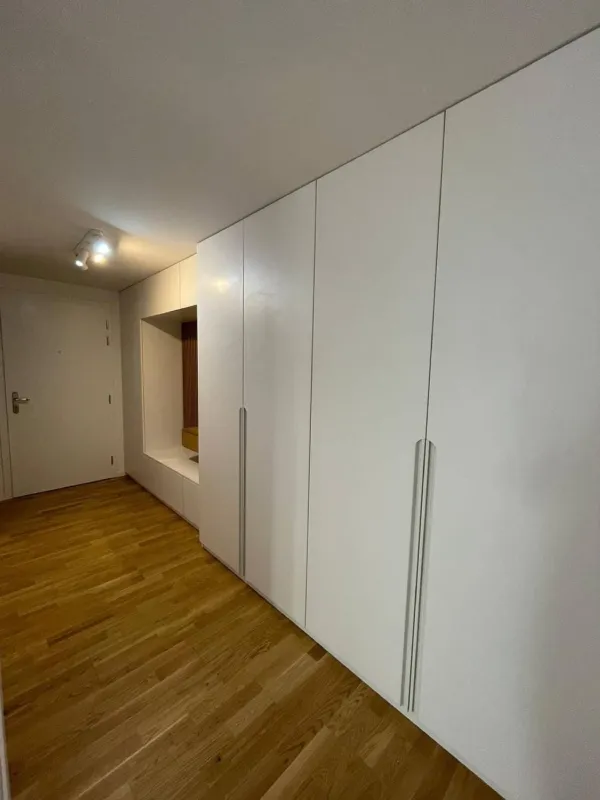 Biela vstavaná skriňa na chodbe s nikou a lavicou
