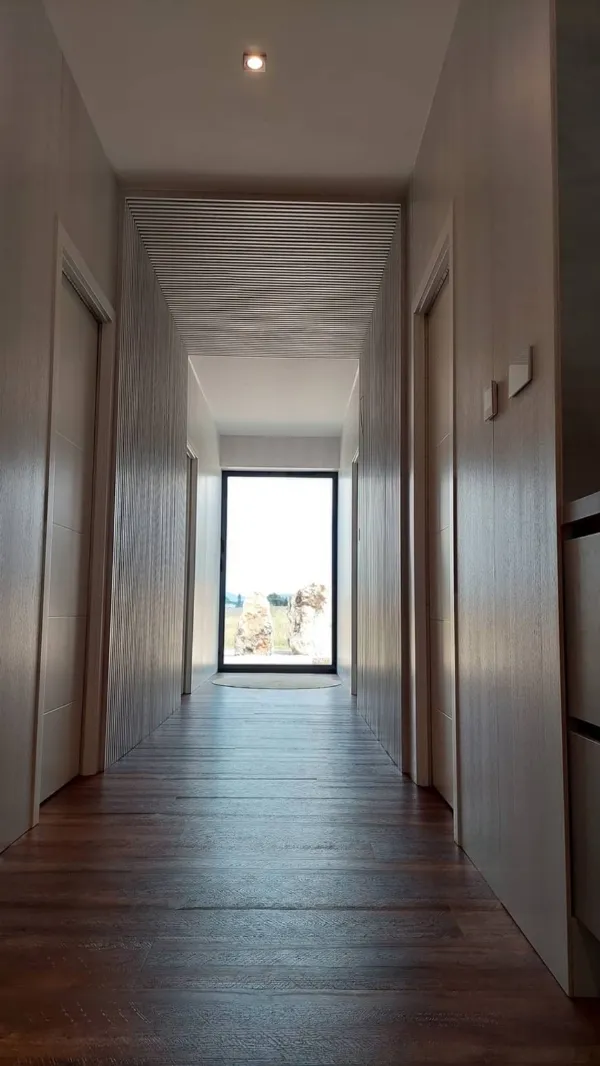 Dlhá chodba s obkladom stien a bezzárubňovými dverami