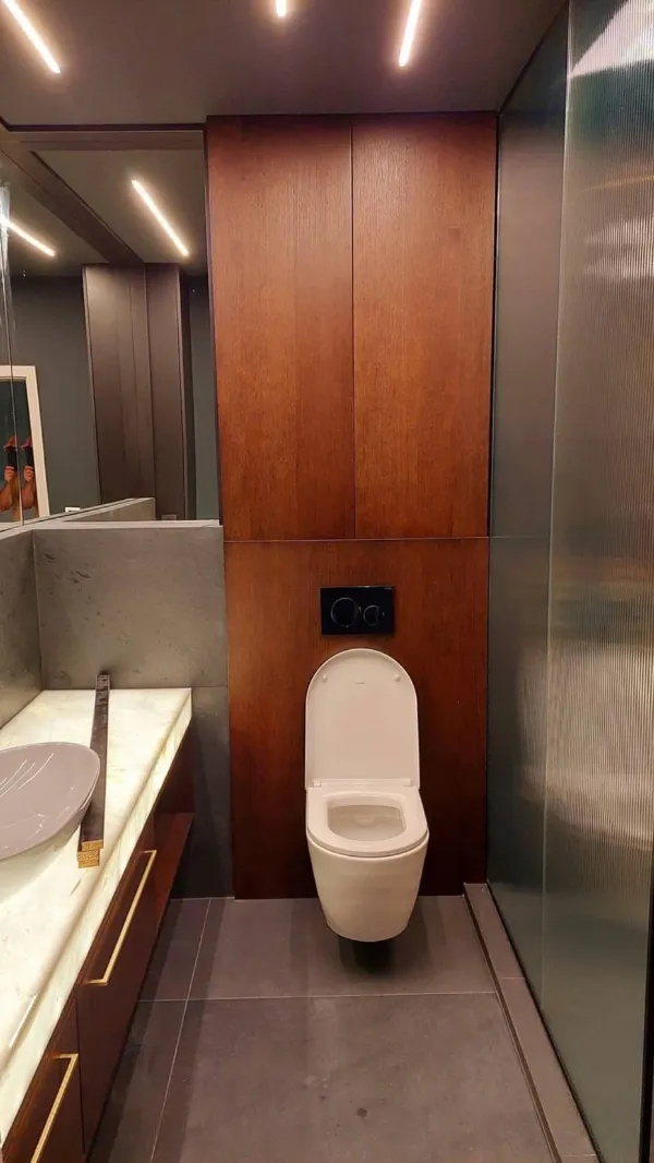 Kúpeľňa s obkladom steny za WC z tmavého dreva a skrinkou pod umývadlo