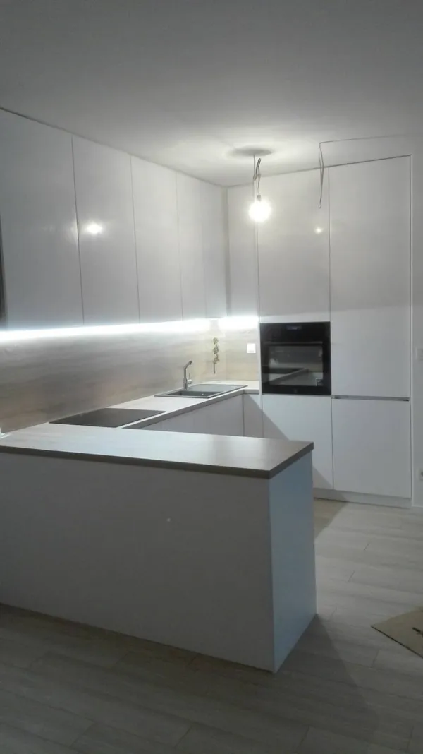 Biela lesklá kuchyňa s polostrovom a LED osvetlením pracovnej dosky